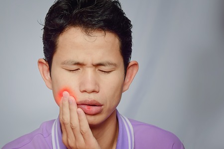 man have  toothache and mouth ulcer on white background,symptoms of toothaches typically involve some kind of ache or pain in the jaws or gumsの写真素材