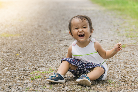 A baby girl crawls around in park with warm filter,are a normal part of a child's development.の写真素材