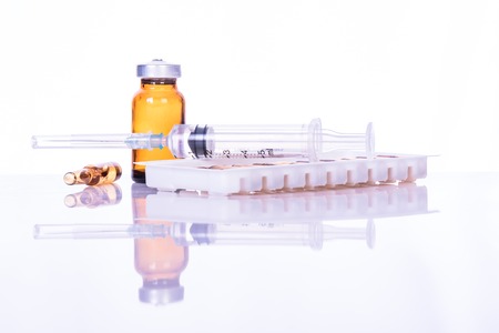 Glass Medicine Vials with syringe on white table for backgroundの写真素材