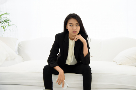 Beautiful asian business woman sitting on white sofa with Confident gestureの写真素材