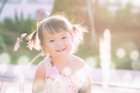 portrait of a little girl in summer nature on sunset time warm tone filterの写真素材