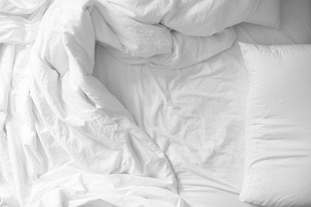 Bed sheets and pillows messed up after nights sleep ,comfort and bedding in a hotel room, concept travel and vacation top viewの写真素材