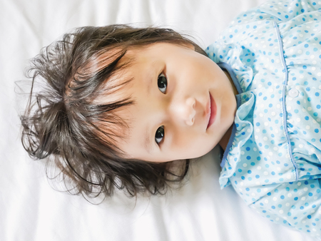 child lying smile on white bedding room with copy space.:soft focusedの写真素材