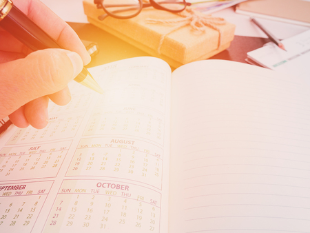 Hand writing blank planning notebook on desk use us organizer schedule life or business planner concept.の写真素材