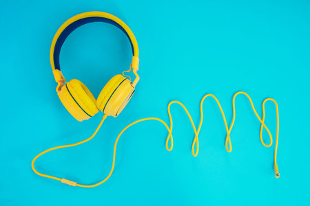 Yellow headphones or earphone computer on a blue pastel background.