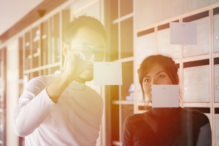 man writing on glass wall transparent idea board thinking with post it stickers.の写真素材