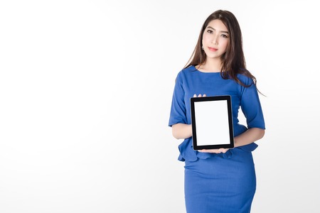 confident young business woman standing and holding blank screen digital tablet for present something on white background.の写真素材