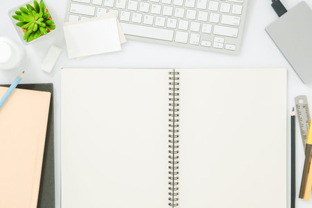 Blank notebook page on modern white office desk table with supplies for mockup. Top view, flat lay...