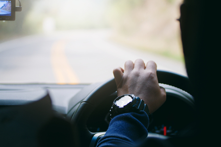 Driver hands holding steering wheel curve road, inside of a car processの写真素材
