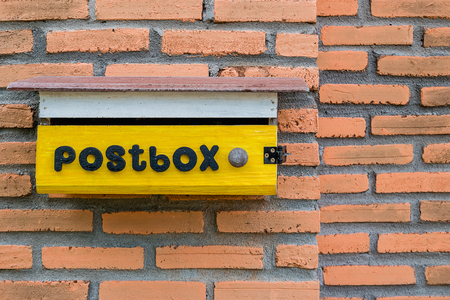 Yellow mailbox on brick home wall backgroundの写真素材
