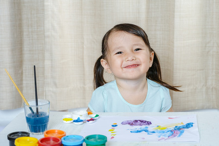 Little Girl Painting with paintbrush and colorful paints children development conceptの写真素材
