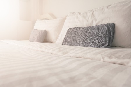 Bedding in bedroom with sunrise effect,clean white bedding sheet and pillows in beauty room interiorの写真素材