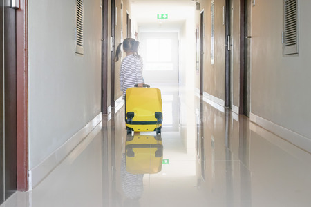 Children or little girl carrying luggage walking on the hallway at the hotel or hostelsの写真素材