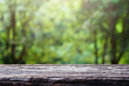 old wooden table top on green blurred abstract background from foliage background. Ready used us...