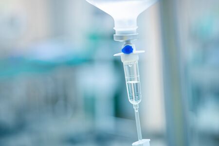 Intravenous therapy iv infusion set and bottle on a pole. Liquid saline is slowly dripping drops of drugs, medicine or antibiotic therapy and surgery recovery in a hospital or clinic.の写真素材