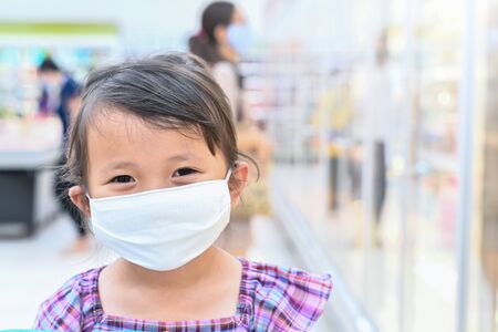 Little girl has fabric mask protect herself from Coronavirus when child go to supermarket with mother after supermarket open again ,child with a mask on nose for safety outdoor public place activityの写真素材