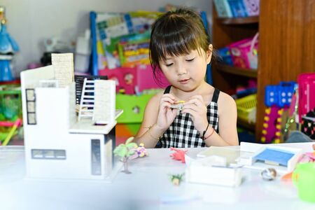 Asian little girl children playing at toy and leaning to enjoy the saturday morning at toy corner home buildingの写真素材