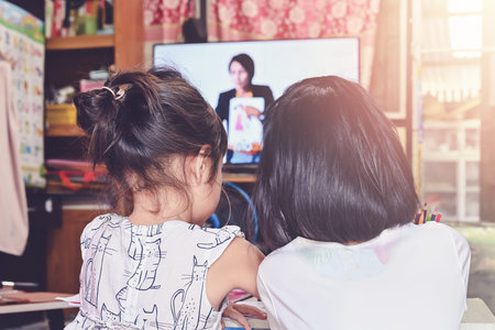 Home School ,close up Schoolgirl learning online sitting on floor and watching television to...