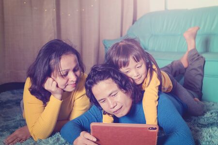Family in living room at night using tablet device watching video happy familyの写真素材