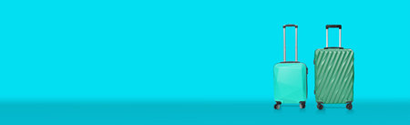 Green tone of plastic suitcases on blue wide banner background. Travel vacation trip concept after lockdown from covid-19.の写真素材