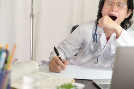 Doctor yawned sleepy had a very exhausting day at work because doctor lack of sleep is bad , Do not have time to sleepの写真素材