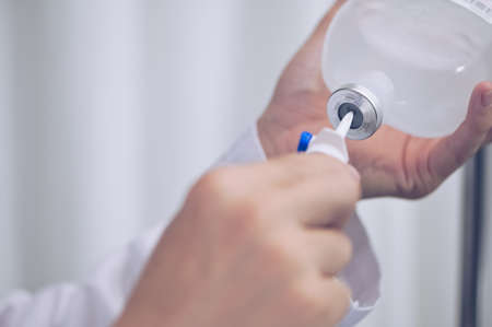 Close up doctor hand injection bottle for saline IV drip Infusionwith IV solution for patient in ward hospital.の写真素材