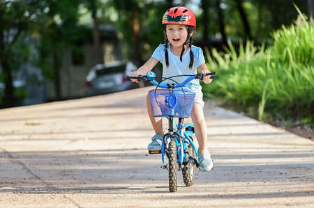 Happy girl riding a bike in garden park . Active child wearing bike helmet. Safety sports leisure with kids conceptの写真素材