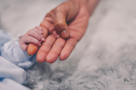 grandmother hand holding newborn baby grandson fingerの写真素材