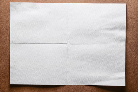 white empty folded sheet of paper on a brown paper background