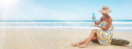 woman pouring applying sunblock cream lotion on beach for broad spectrum UVA, UVB sun protectionの写真素材