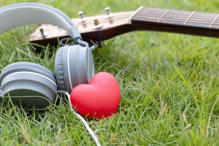 Love music. Red heart and headphones music and guitar classic on green fields. Sound of life. Acoustic music.の写真素材