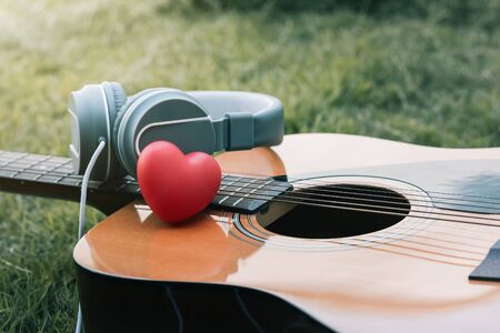 Love music. Red heart and headphones music and guitar on fields. Sound of life. Acoustic music and vintage style.の写真素材