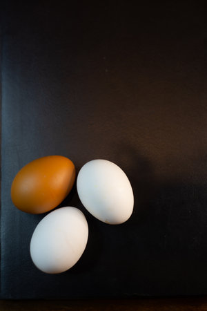 Three chicken eggs on a black background. Top view. Copy space.の写真素材