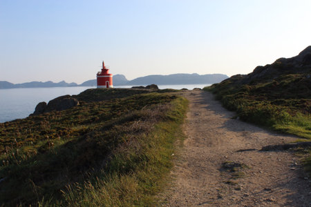 Red and white lighthouse in Punta Robaleira (Galicia, Spain), In the background are the islands C?es.の写真素材