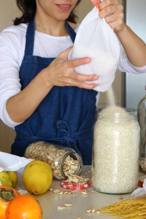Housewife uses reusable glass containers and cloth bags to buy food. Zero Waste Grocery Shopping. Plastic Free Lifestyle Shop in Bulk Zero wasteの写真素材