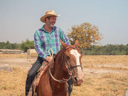 Cowboy is riding his horse on a cattle farm with dry landの写真素材