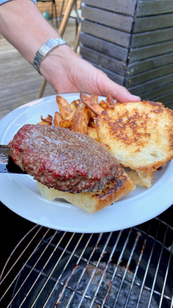 Barbecued burger with fries on a plateの写真素材