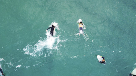 Surfers in the water and on their surfboards are waiting for their next wave on a beach in Portugal