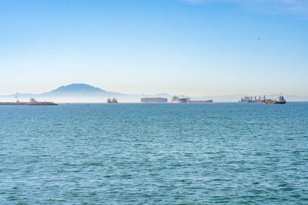 Cargo Ships Anchored in the bay with a misty coast behindの写真素材