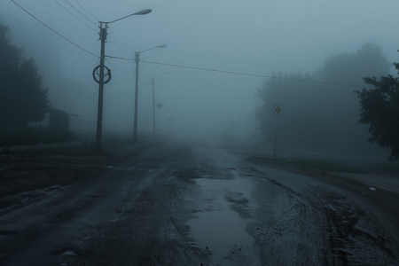 Silhouette of a lonely man standing on the foggy roadの写真素材