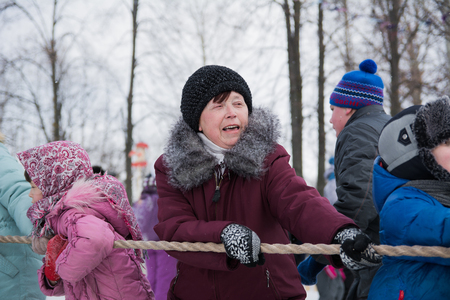 Yoshkar-Ola, Russia - February 26, 2016 Tug of war during the Carnival. Emotional portrait of a woman tugging on a rope.のeditorial素材