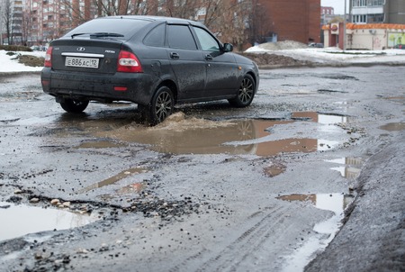 Yoshkar-Ola, Russia - April 4, 2016 Lada Priora car rides along the road with a terrible condition of asphalt coveringのeditorial素材