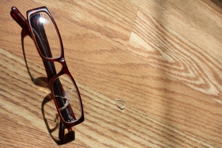prescription eyeglasses with a broken lens on wooden floorの写真素材