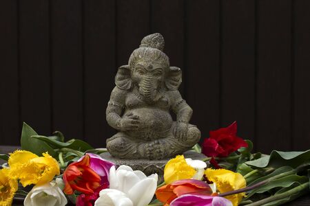 Ganesh decorative stone statue in the garden with flowersの写真素材