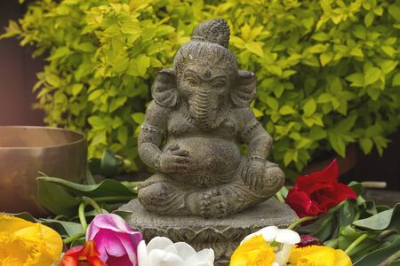 Ganesh decorative stone statue in the garden with flowersの写真素材