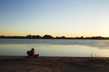 Woman reading in the shore of a lakeの写真素材