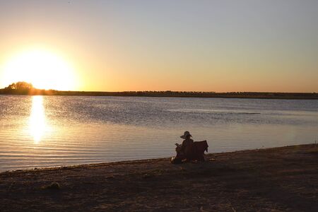 Woman reading in the shore of a lakeの写真素材