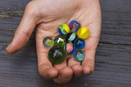 Hands holding a set of colorful marblesの写真素材