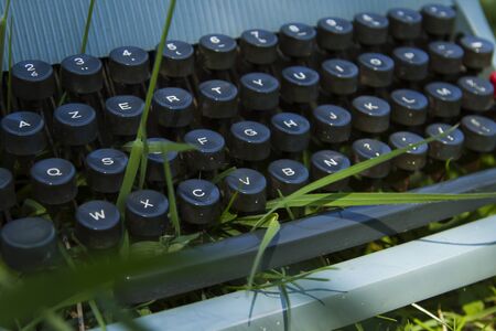 Old blue typewriter on the green grassの写真素材