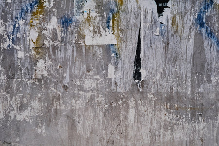 Old bulleting board wall with rests of worn peeled advertising posters, grunge background or textureの写真素材